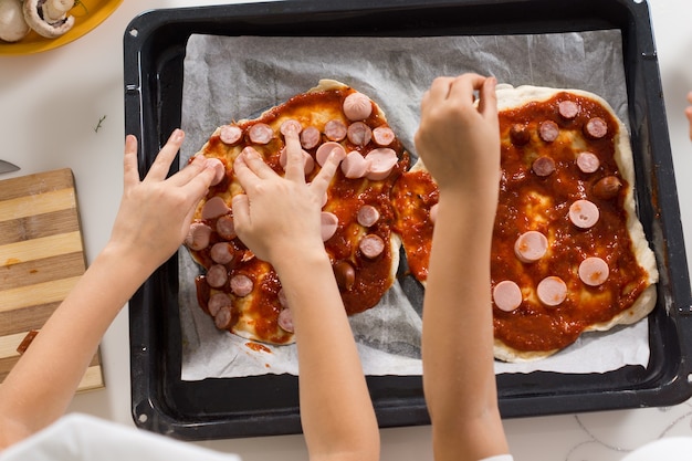 Two young children making homemade pizza