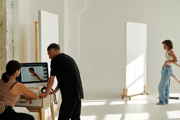 Two young colleagues in casualwear discussing new shots on computer screen