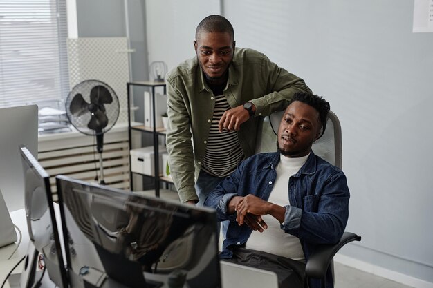 Two young colleagues discussing working information on computer screen