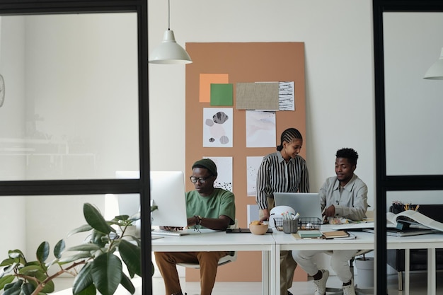 Two young colleagues preparing presentation next to male designer