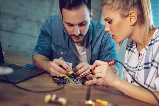 2人の若い同僚の技術者が電子機器の修理に焦点を合わせました。