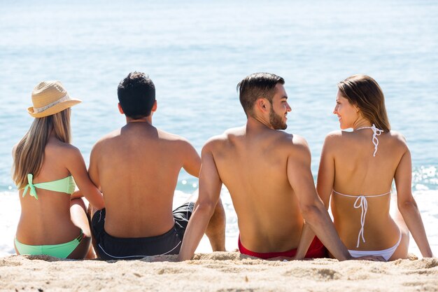 Foto due giovani coppie sulla spiaggia di sabbia