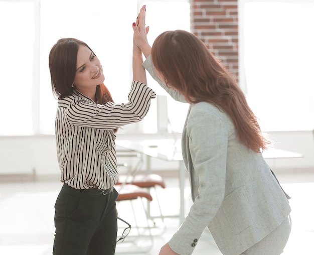 Two young coworkers giving each other a high five success concept