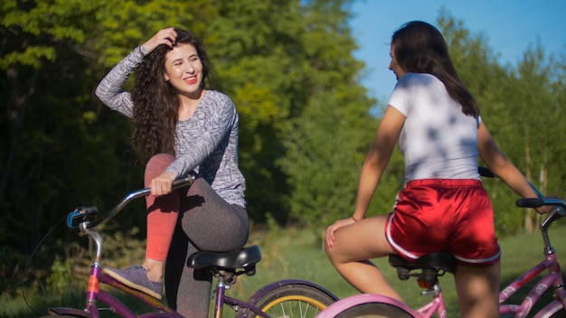 Two young cyclists communicate and laugh on a Cycling trip in the Park on a Sunny summer day