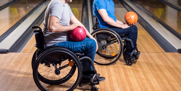 Two young disabled men in wheelchairs playing bowling in the club