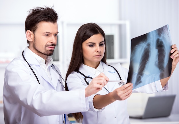 Two young doctors are looking at X-ray in medical office.