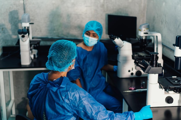 実験室で顕微鏡を通して見ている2人の若い医者