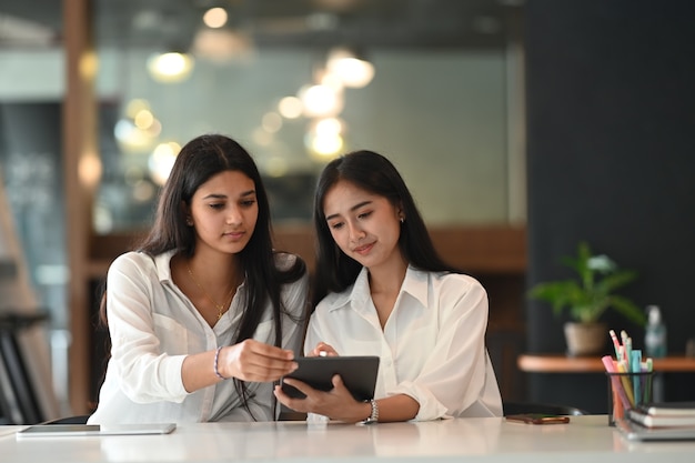 Two young female freelancer are working on laptop at the office