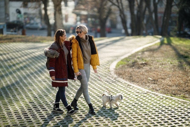 Photo a two young female friends walking with their pet shih tzu dog by the city street.