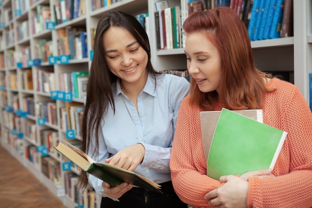 Две молодые студентки читают вместе в книжном магазине