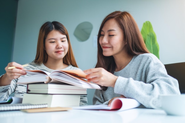 Two young female students tutoring and catching up workbook together