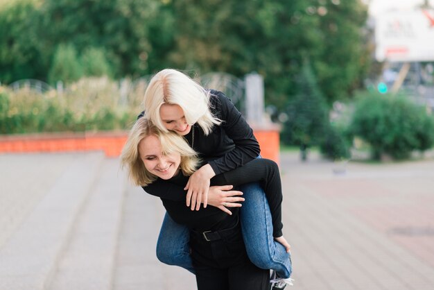 Two young females walking smiling embracing and kissing outdoor in the city