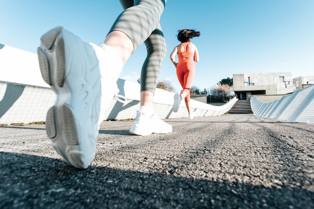 Two young fitness woman training running outdoors doing exercise wearing sportswear. Fitness girls working out together. Low angle image moving motion image. Healthy sport life