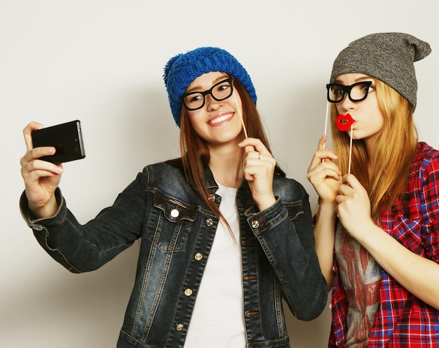 Two young funny women taking selfie with mobile phone