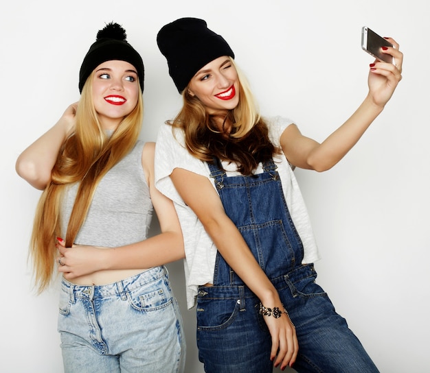 Photo two young funny women taking selfie with mobile phone