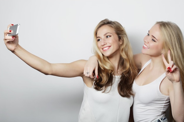 Photo two young funny women taking selfie with mobile phone