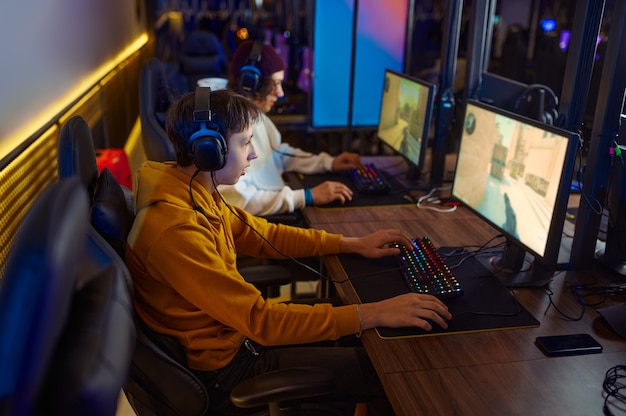 Two young gamers in headsets play in video game club