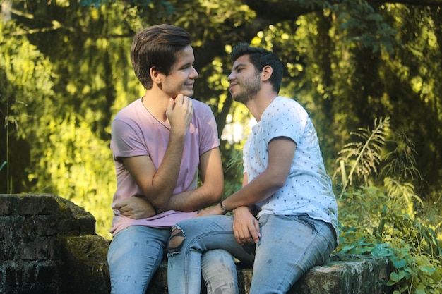 Two young gay men kiss in a nature park