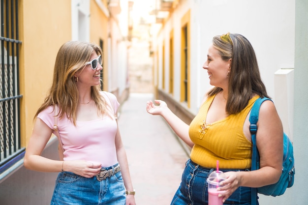 Two young girl friends greeting each other on the street during their summer vacation