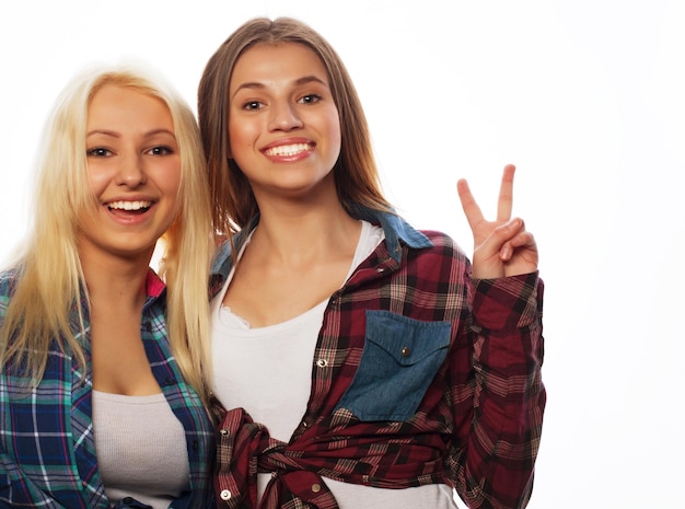 Фото Две молодые подруги стоят вместе и веселятся показывая знаки руками глядя в камеру