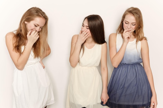 Two young girl friends standing together and having fun shyness and laughter