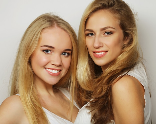 Two young girl friends standing together and having fun.