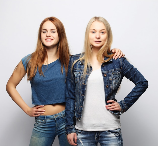 Two young girl friends standing together and having fun.