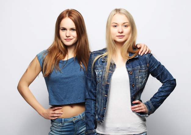 Two young girl friends standing together and having fun.