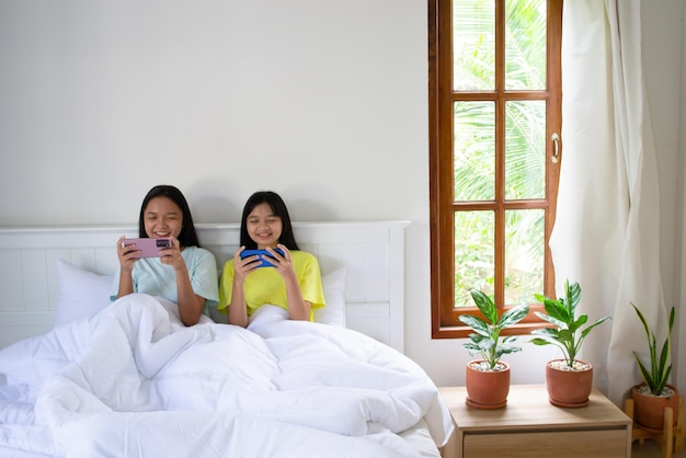 Two young girl playing game with smartphone on bedroom in house