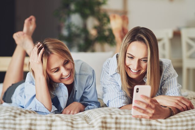 ベッドの上で自分撮りをしている2人の若いガールフレンド。高品質の写真