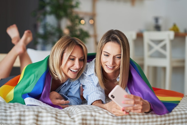 Two young girlfriends on the bed taking selfie. High quality photo