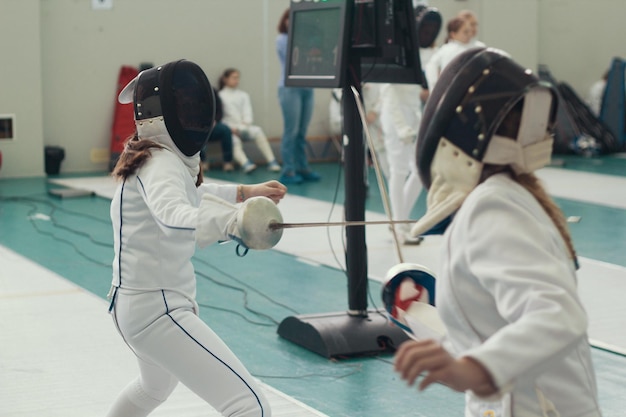 Photo two young girls fencers having fencing duel on tournament