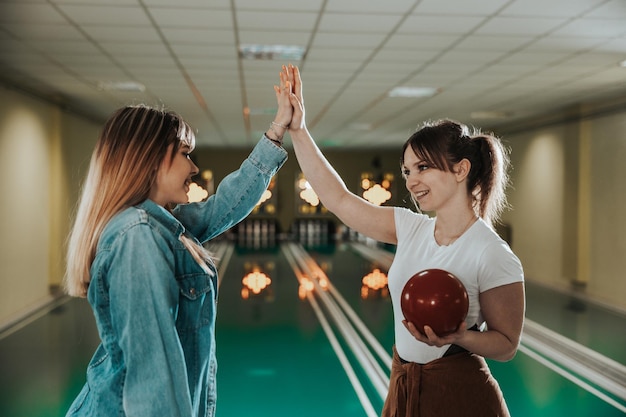 Two young girls giving high five at the bowling club.