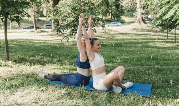 Two young girls practice yoga exercises in an outdoor park healthy lifestyle