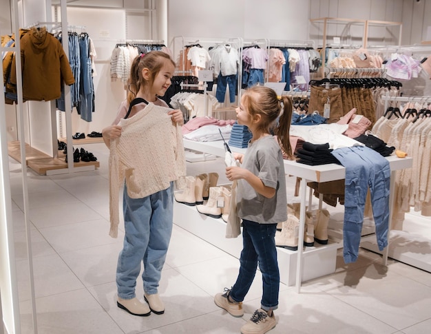 two young girls shopping for clothes in a cozy kids store during daytime