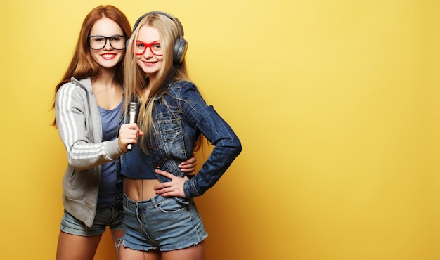 Two young girls singing over yellow background