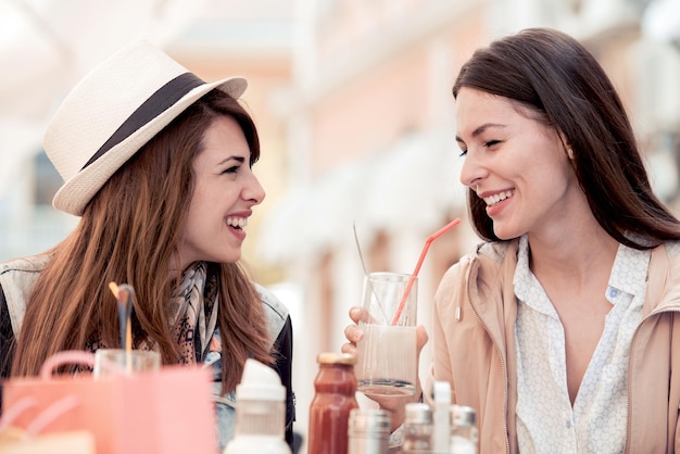 Two young girls talking and smiling in cafe