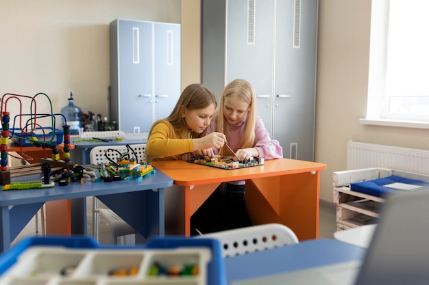 Two young girls using electronic parts to build a drone