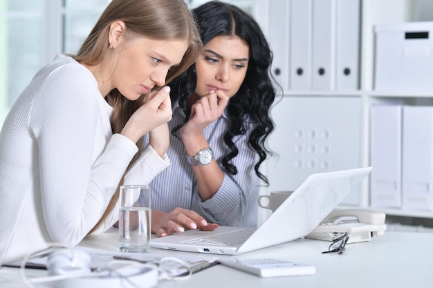 Two young girls working at office using laptop