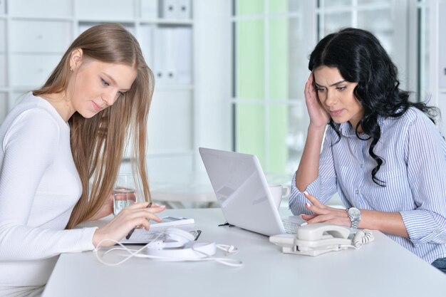 Two young girls working at office using laptop