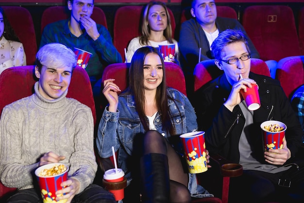 Two young guys and a girl watching a Comedy in a movie theater