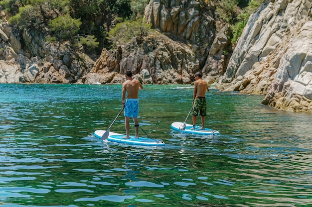 Two young guys ride a paddle surf in the sea