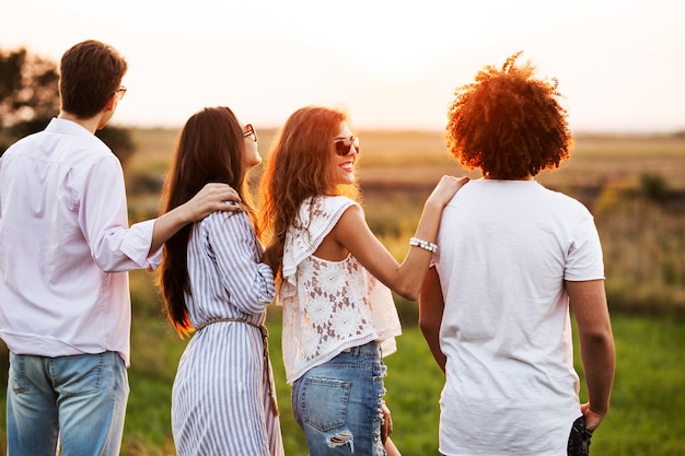 Two young guys and two girls dressed in a stylish clothes are standing in the field