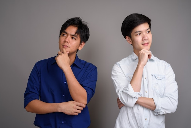 two young handsome Asian men on gray