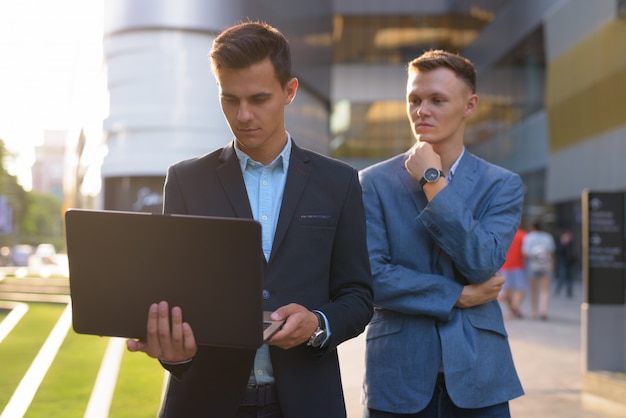 Two young handsome businessmen working together outside the buildingding