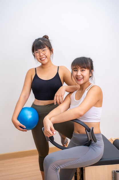 彼らのトレーニング運動休憩中にカメラにポーズをとって笑っている2人の若い幸せなアジアの女性