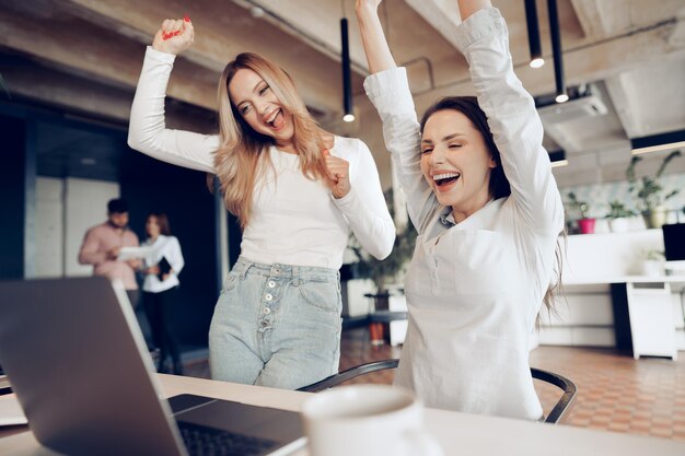 two young happy businesswomen celebrating project success in office