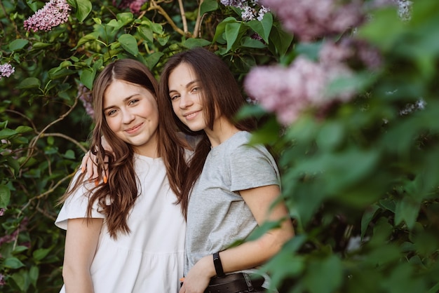 2人の若い幸せな10代の少女が緑の芝生の公園で休んでいます。女性の友情。ソフトセレクティブフォーカス。