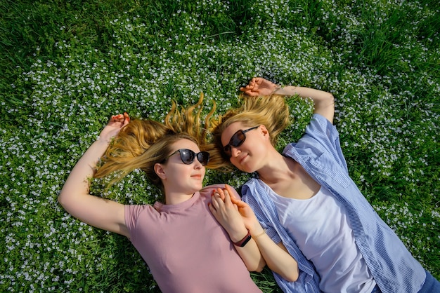 Two young happy woman on green grass outdoor