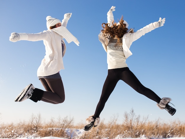 Two young happy woman, two friends, having fun in bright winter day. Lifestyle concept